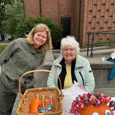 Two women smile over fall giveaways at Fall Festival.