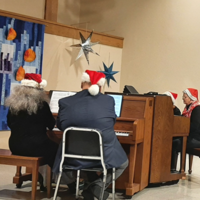 Photo shows a piano quartet with players in Santa hats.