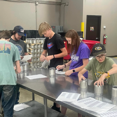 Youth labeling donated canned food for donations.